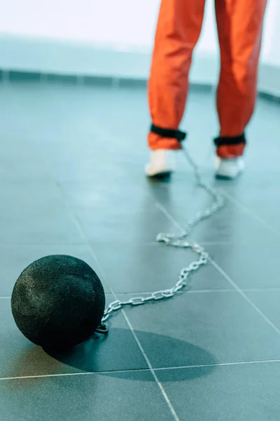 Обрезанное изображение заключенного в оранжевой форме с привязанным к ноге весом — стоковое фото
