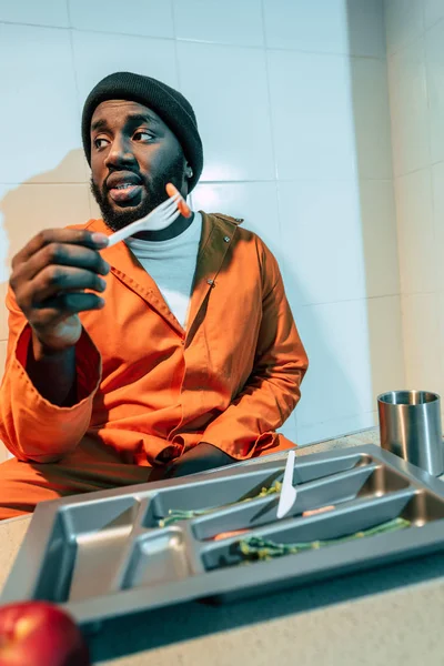 African american criminal eating in prison cell — Stock Photo