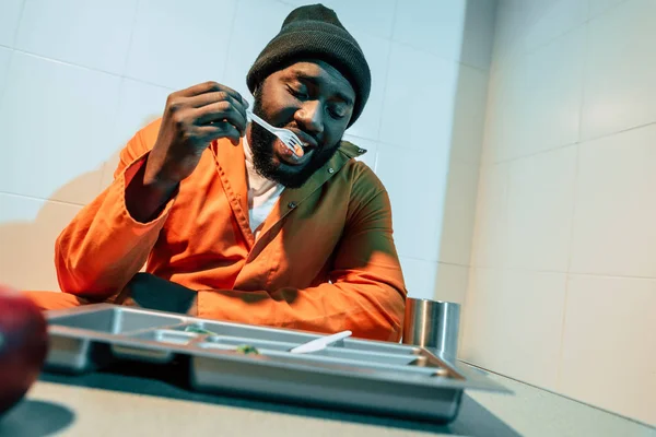 African american convict eating in prison cell — Stock Photo
