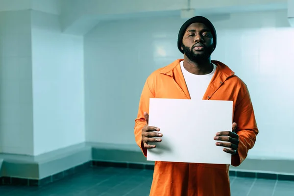 African american prisoner holding blank placard and looking at camera — Stock Photo