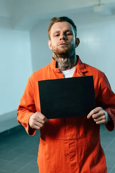 Prisoner holding blackboard and looking at camera — Stock Photo