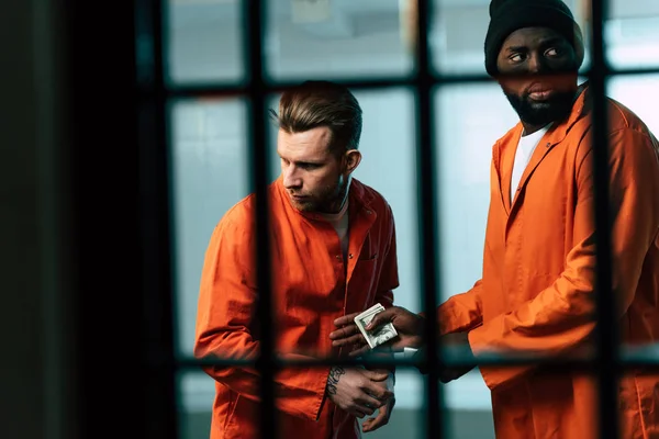 Prisionero comprando drogas a un preso afroamericano en la habitación de la prisión - foto de stock