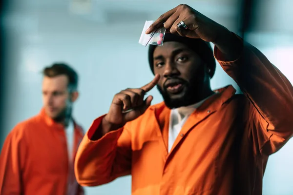 African american prisoner pointing on drugs at prison cell — Stock Photo