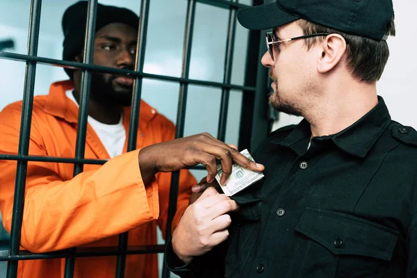 Prisonnier afro-américain donnant de l'argent à un agent de prison comme pot-de-vin — Photo de stock