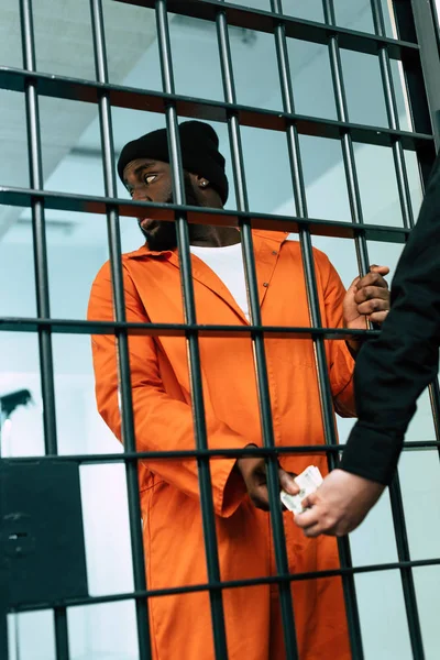 Imagem cortada de prisioneiro afro-americano dando dinheiro para guarda de segurança como suborno — Fotografia de Stock