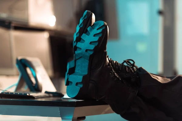 Cropped image of prison guard sitting with legs on table — Stock Photo