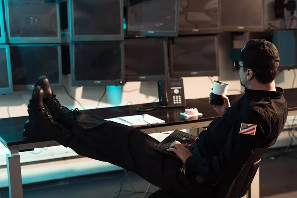 Prison guard sitting with legs on table and monitoring people in jail — Stock Photo