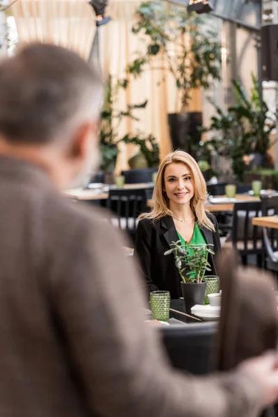 Selective focus of woman looking at man while sitting at table in cafe — Stock Photo