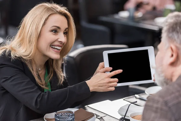 Side view of businesswoman with tablet during meeting with colleague in cafe — Stock Photo