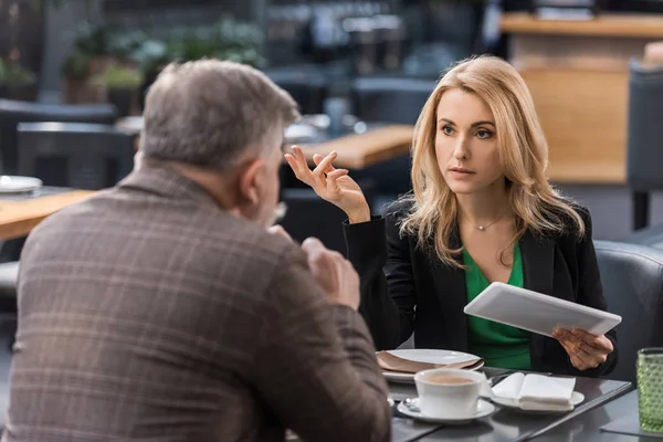 Businesswoman with tablet having business meeting with colleague in cafe — Stock Photo