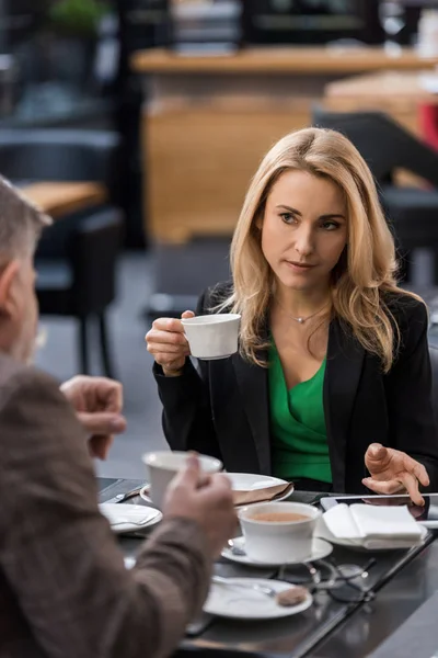 Vista parcial de la gente de negocios con tazas de café teniendo reunión de negocios en la cafetería - foto de stock