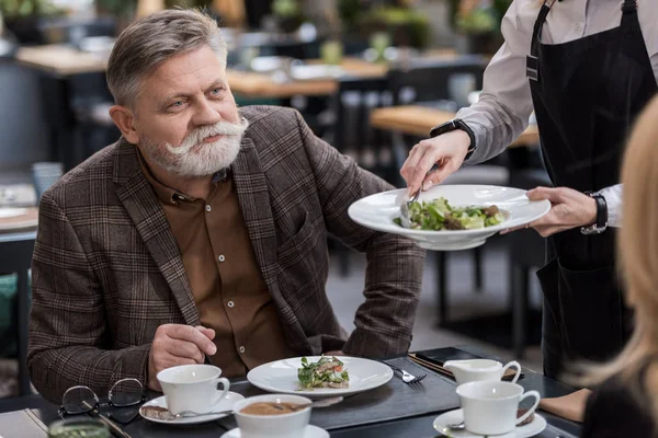 Vue partielle d'un homme et d'une femme âgés dînant ensemble au restaurant — Photo de stock