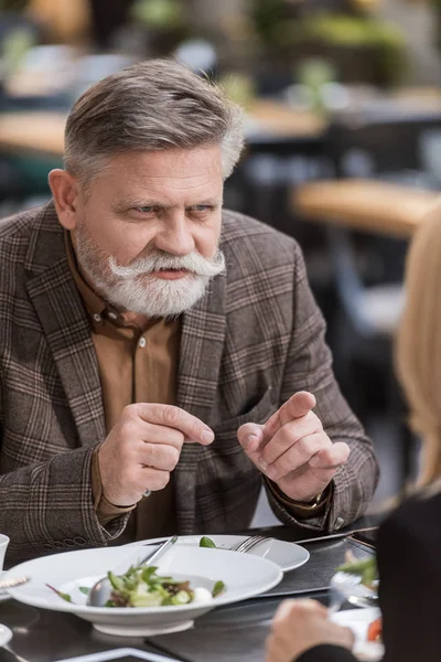 Частичный вид пожилых мужчин и женщин, ужинающих вместе в ресторане — стоковое фото