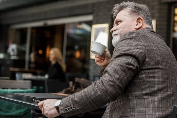 Side view of senior man with cup of coffee in cafe — Stock Photo