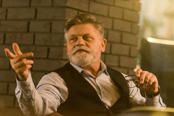 Retrato de homem barbudo sênior com óculos chamando garçom no café — Fotografia de Stock