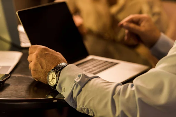 Colpo ritagliato di uomo d'affari seduto a tavola con computer portatile in caffè — Foto stock