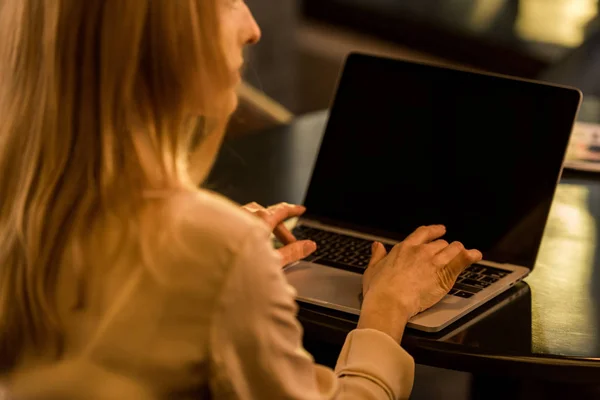 Vista parcial de la mujer de negocios utilizando el ordenador portátil con pantalla en blanco en la cafetería - foto de stock