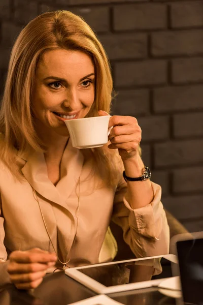 Ritratto di donna d'affari sorridente con tazza di caffè seduta a tavola con tavoletta in caffè — Foto stock
