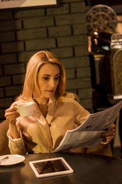 Retrato de empresária com xícara de café lendo jornal no café — Fotografia de Stock