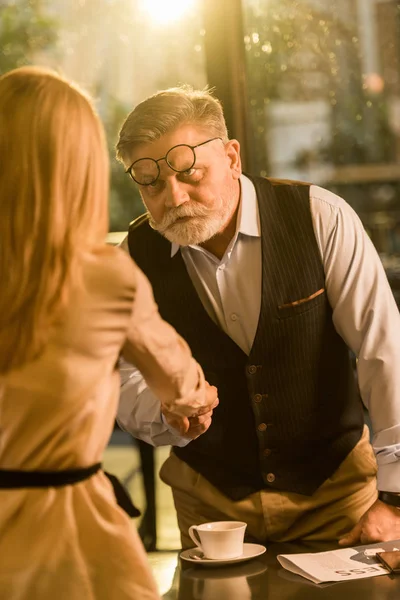 Partial view of business partners shaking hands after business meeting in cafe — Stock Photo