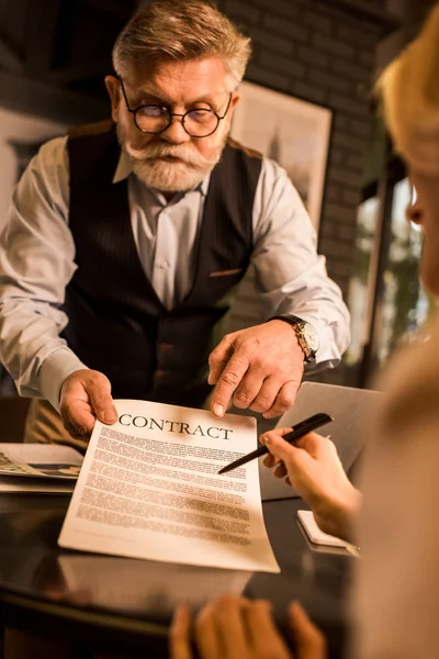 Vista parcial del socio de negocios que firma el contrato en la reunión de negocios en la cafetería - foto de stock