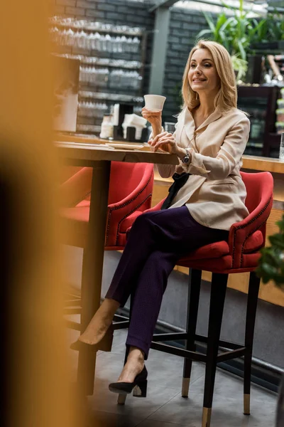 Enfoque selectivo de la mujer sonriente con taza de café en la cafetería - foto de stock