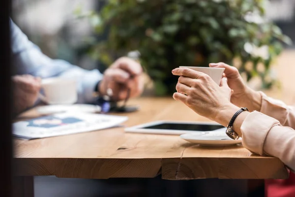 Schnappschuss einer Frau mit einer Tasse Kaffee in der Hand, die am Tisch im Café sitzt — Stockfoto