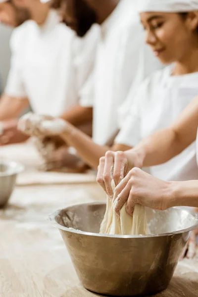 Cropped shot of group of baking manufacture workers kneading dough — Stock Photo