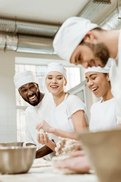 Groupe de travailleurs de la boulangerie multiethnique pétrissant la pâte ensemble — Photo de stock