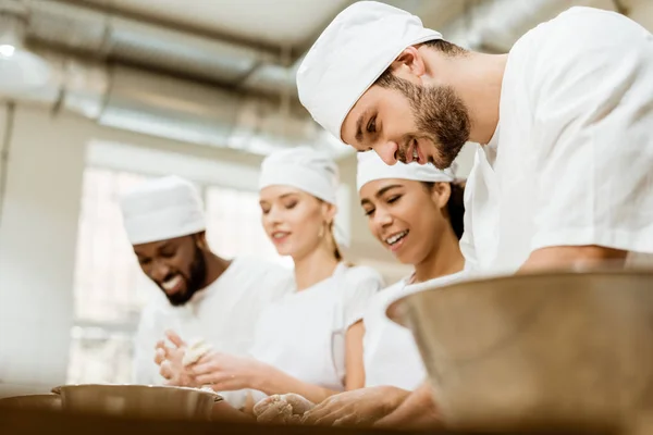 Groupe de travailleurs heureux boulangerie fabrication pétrissage pâte ensemble — Photo de stock