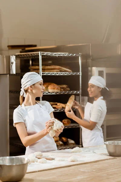Young female bakers working together at baking manufacture — Stock Photo