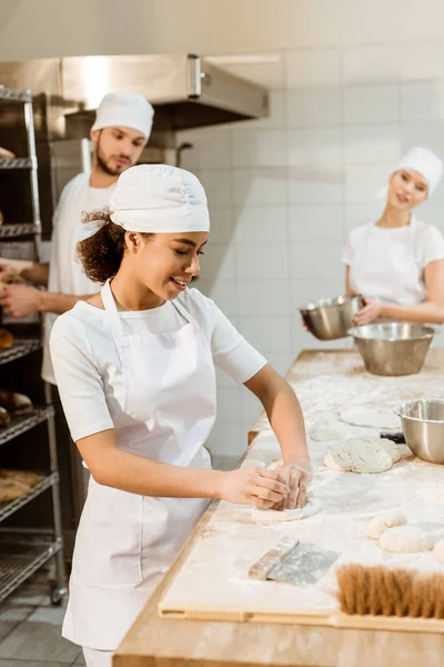 Équipe multiethnique de boulangers travaillant ensemble à la fabrication de pâtisseries — Photo de stock