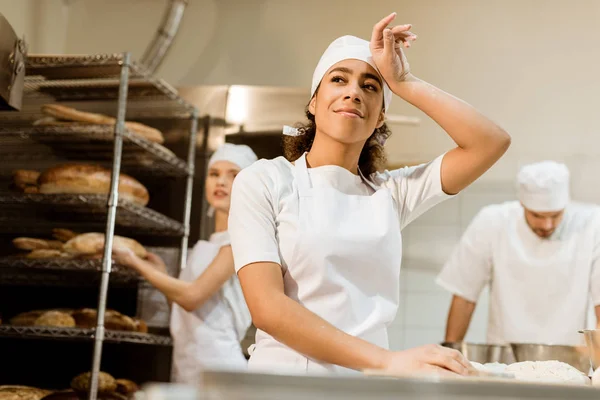 Щаслива і втомлена жінка-пекарня, що працює на хлібопекарському виробництві — стокове фото