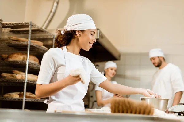 Equipo multiétnico de panaderos que trabajan juntos en la fabricación de panadería - foto de stock