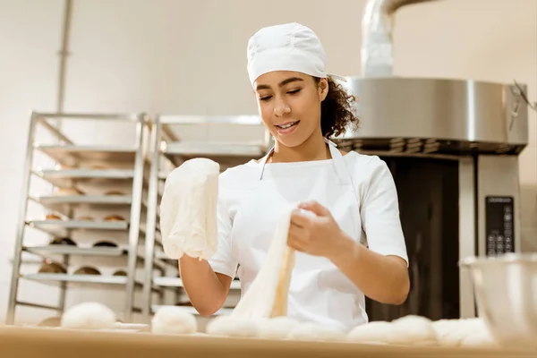Panadero femenino que prepara la masa para la pastelería en la fabricación de la hornada - foto de stock