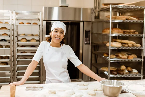Boulanger femelle debout sur le lieu de travail sur la fabrication de cuisson — Photo de stock