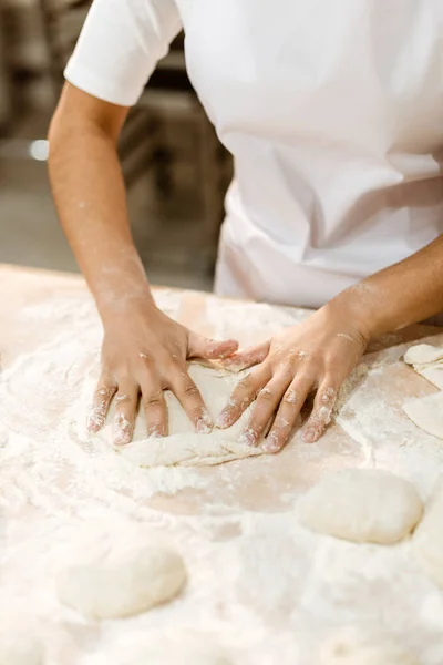 Tiro recortado de panadero hembra amasando masa para pastelería en mesa desordenada - foto de stock