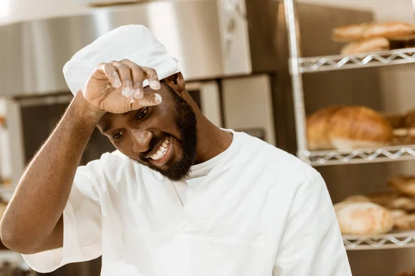 Overworked african american baker wiping sweat on baking manufacture — Stock Photo