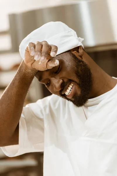 Tired african american baker wiping sweat on baking manufacture — Stock Photo