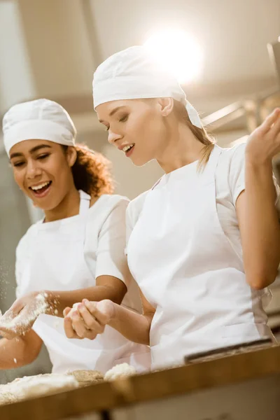 Attractive female bakers kneading dough together at baking manufacture — Stock Photo