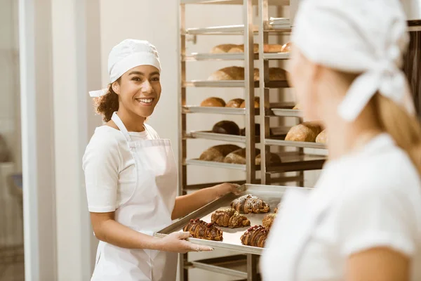 Female bakers working together at baking manufacture abd talking — Stock Photo