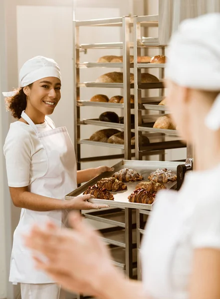 Panaderos jóvenes que trabajan juntos en la fabricación de hornear abd hablar - foto de stock