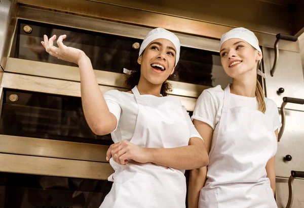 Panaderos femeninos felices charlando en la fabricación de hornear - foto de stock