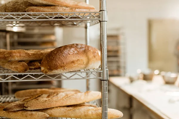 Regale mit leckerem frisch gebackenem Brot auf Backherstellung — Stockfoto