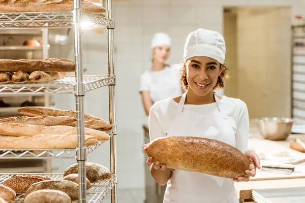 Boulanger afro-américain femelle avec pain frais à la boulangerie — Photo de stock