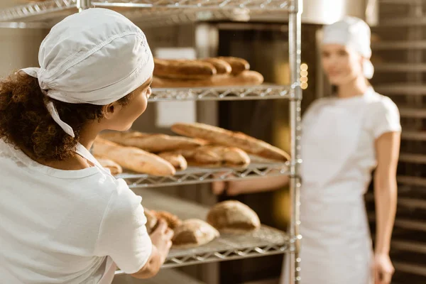 Female bakers working together at baking manufacture and chatting — Stock Photo