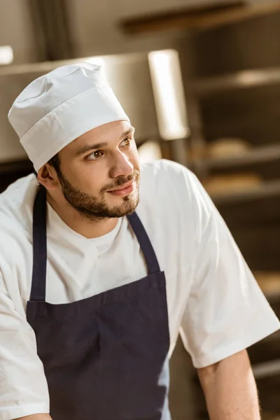 Close-up portrait of handsome young baker on baking manufacture — Stock Photo