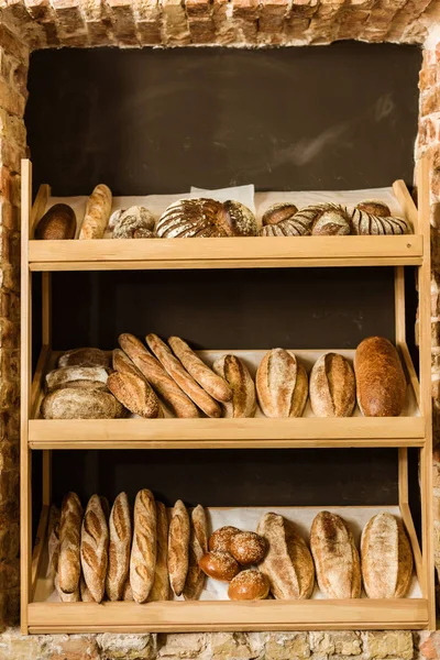 Pão rural variado nas prateleiras da pastelaria — Fotografia de Stock