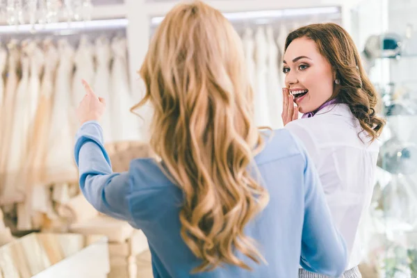 Donne sorridenti che scelgono abiti da sposa in atelier di nozze — Foto stock