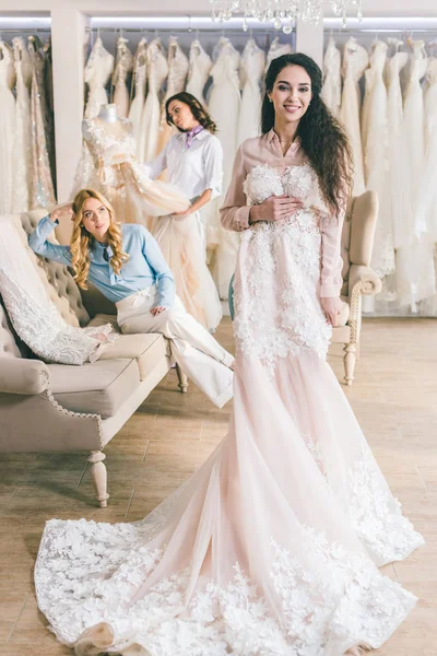Joven novia y damas de honor sosteniendo vestidos en atelier de boda - foto de stock